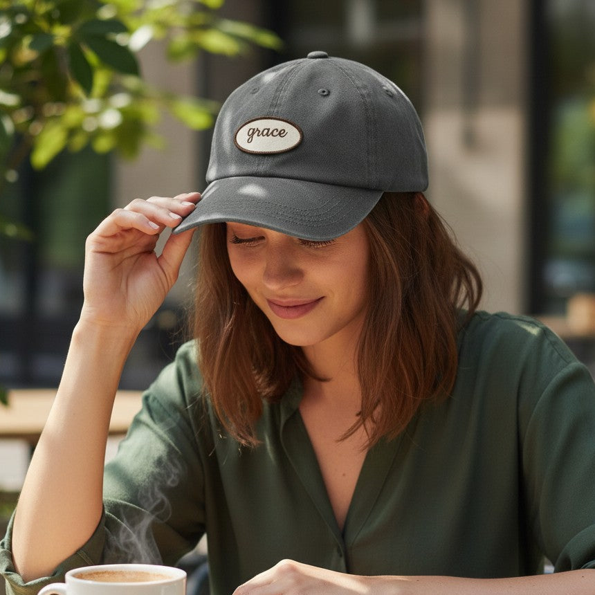Woman wearing a cap, holding a steaming cup of coffee, and looking at a notebook outdoors.