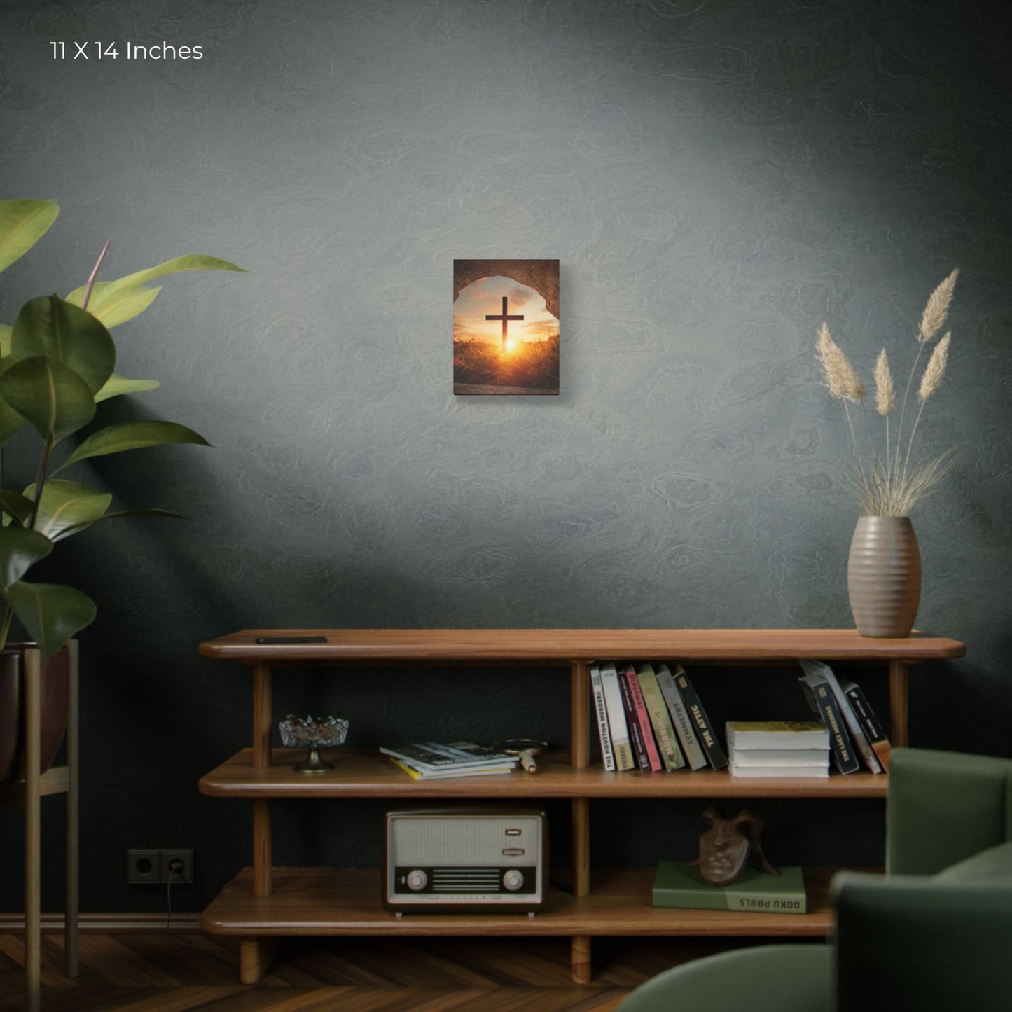 Wall art with a cross and sunset displayed on a wall above a wooden shelf with books and decor.
