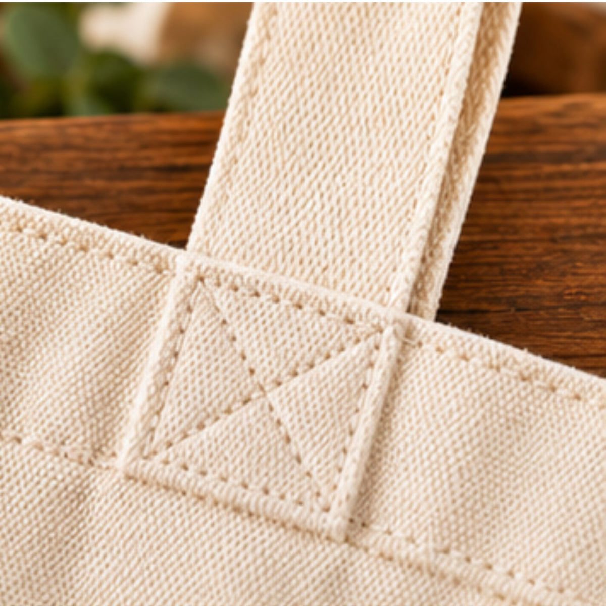 Close-up of the cream canvas tote handle attachment with square and cross stitching.