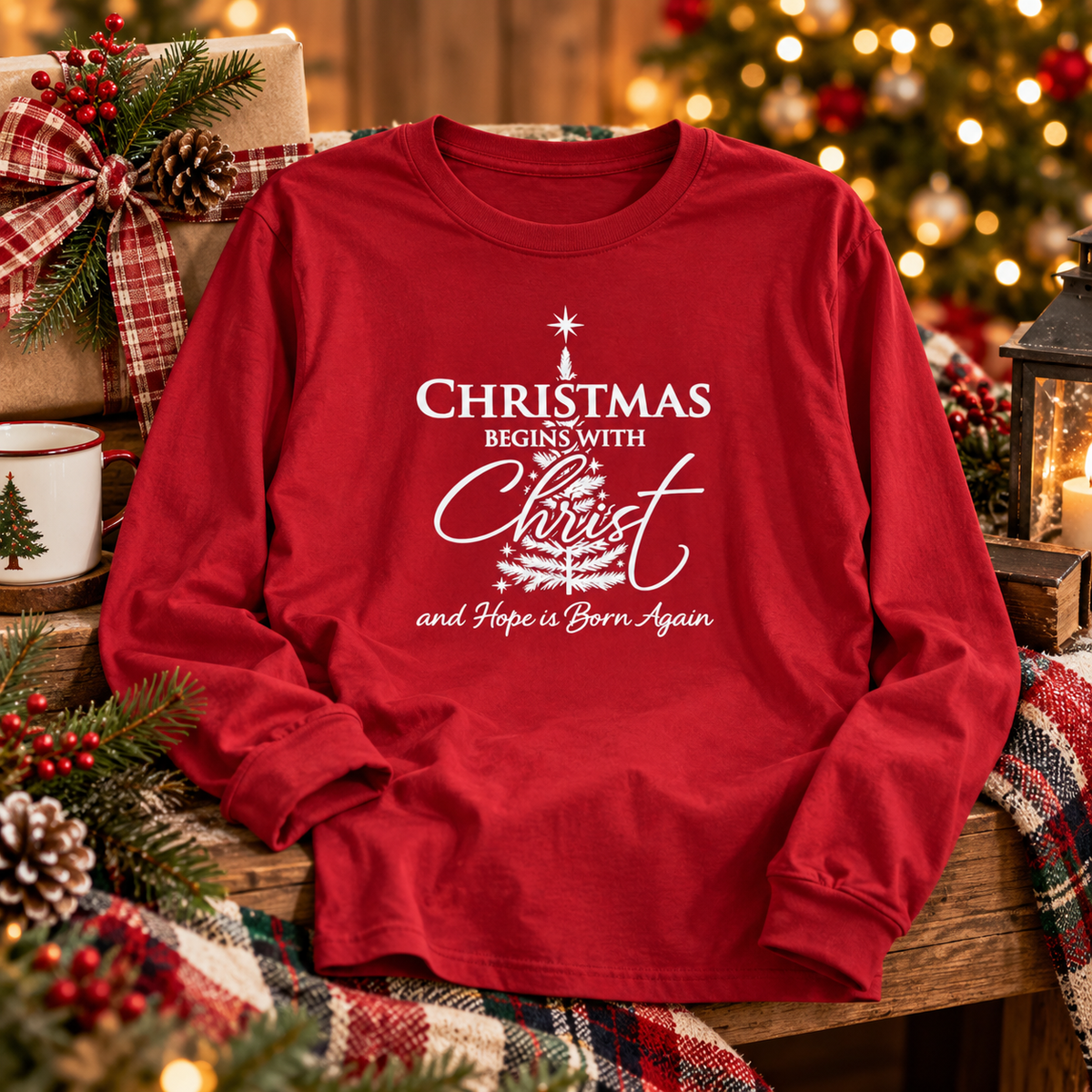 Red Christmas Begins With Christ long-sleeve shirt with front design, displayed among Christmas gifts and greenery