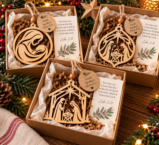 Three wooden Nativity Christmas ornaments individually presented in kraft gift boxes with tissue paper, natural twine, olive wood beads, and Luke 2:11 Scripture cards.