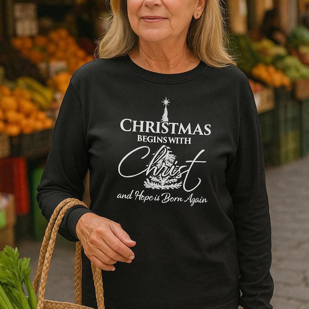 Woman wearing a black long-sleeve shirt with a Christmas-themed message at an outdoor market.