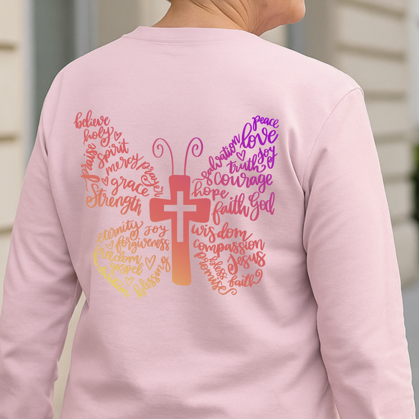 Pink long-sleeve shirt with a colorful design on the back featuring a cross and text.