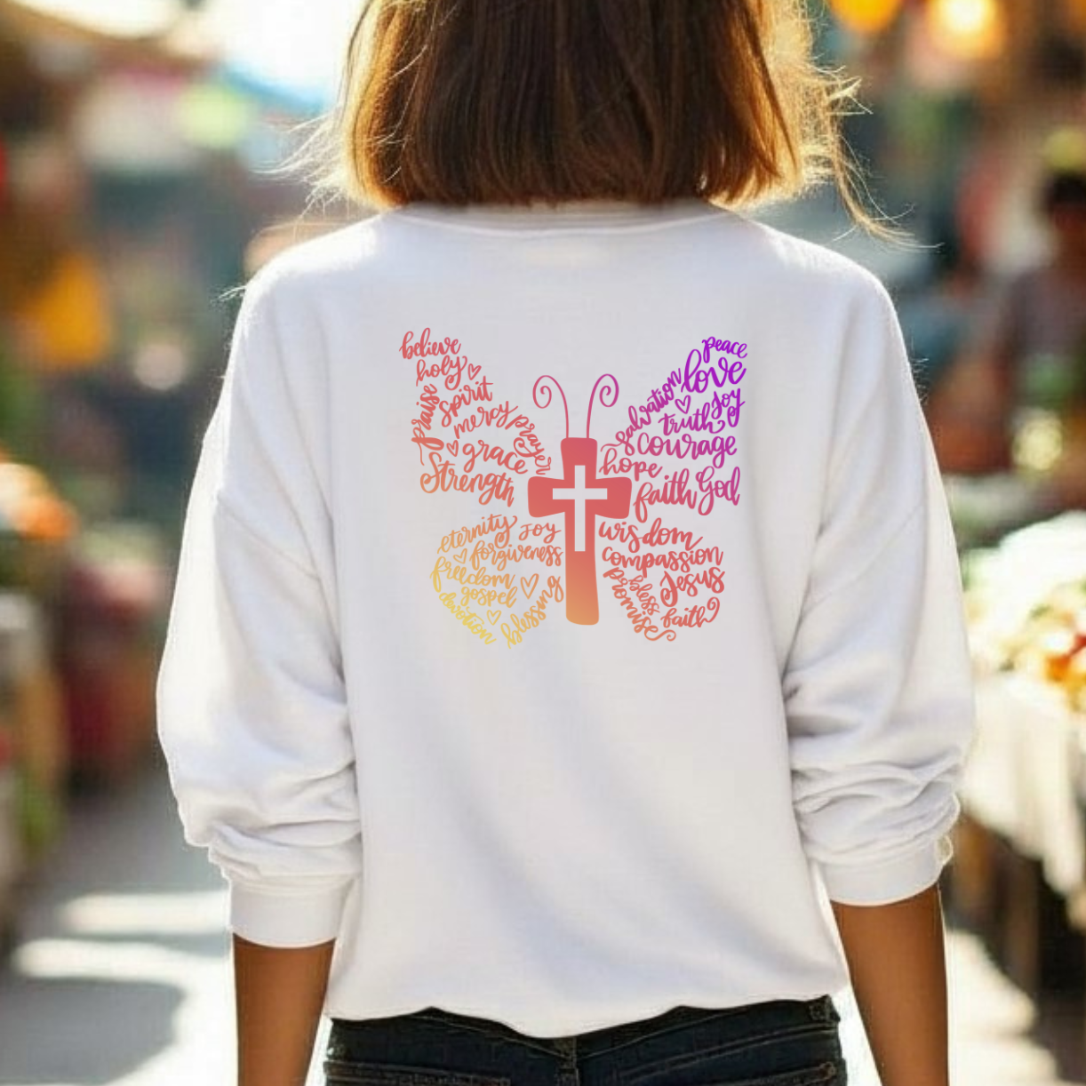 Person wearing a white sweatshirt with colorful text and graphics in an outdoor market setting