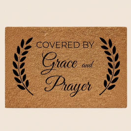 Doormat with 'Covered by Grace and Prayer' text on a beige background