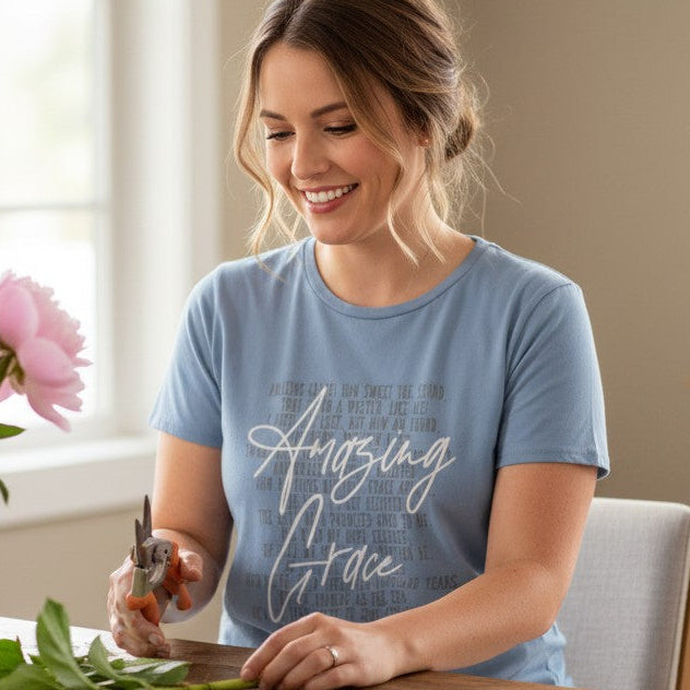 Woman arranging flowers in a vase in a bright room with plants.