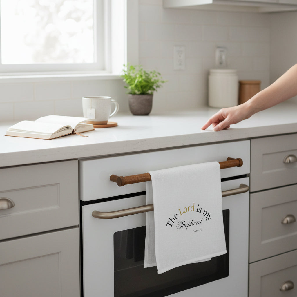 Kitchen scene with a towel hanging on an oven handle, a cup, and book on the counter.