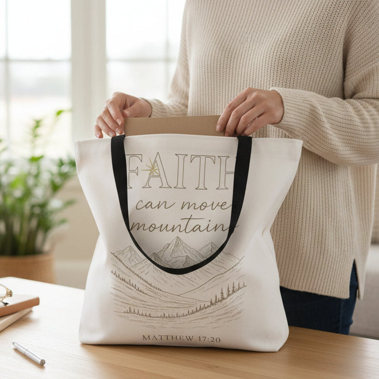 Person holding a tote bag with 'Faith can move mountains' text in a living room setting.
