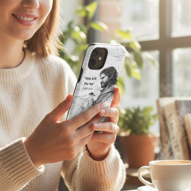 Woman holding a phone with a design, sitting at a table with a cup of coffee and notebook.